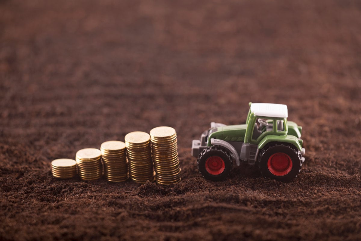 toy-tractor-near-stacked-coins-on-dirt