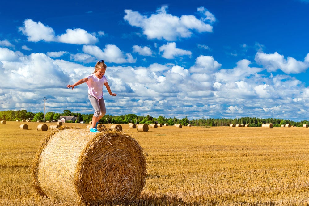 Child balancing on top of a bail of hay