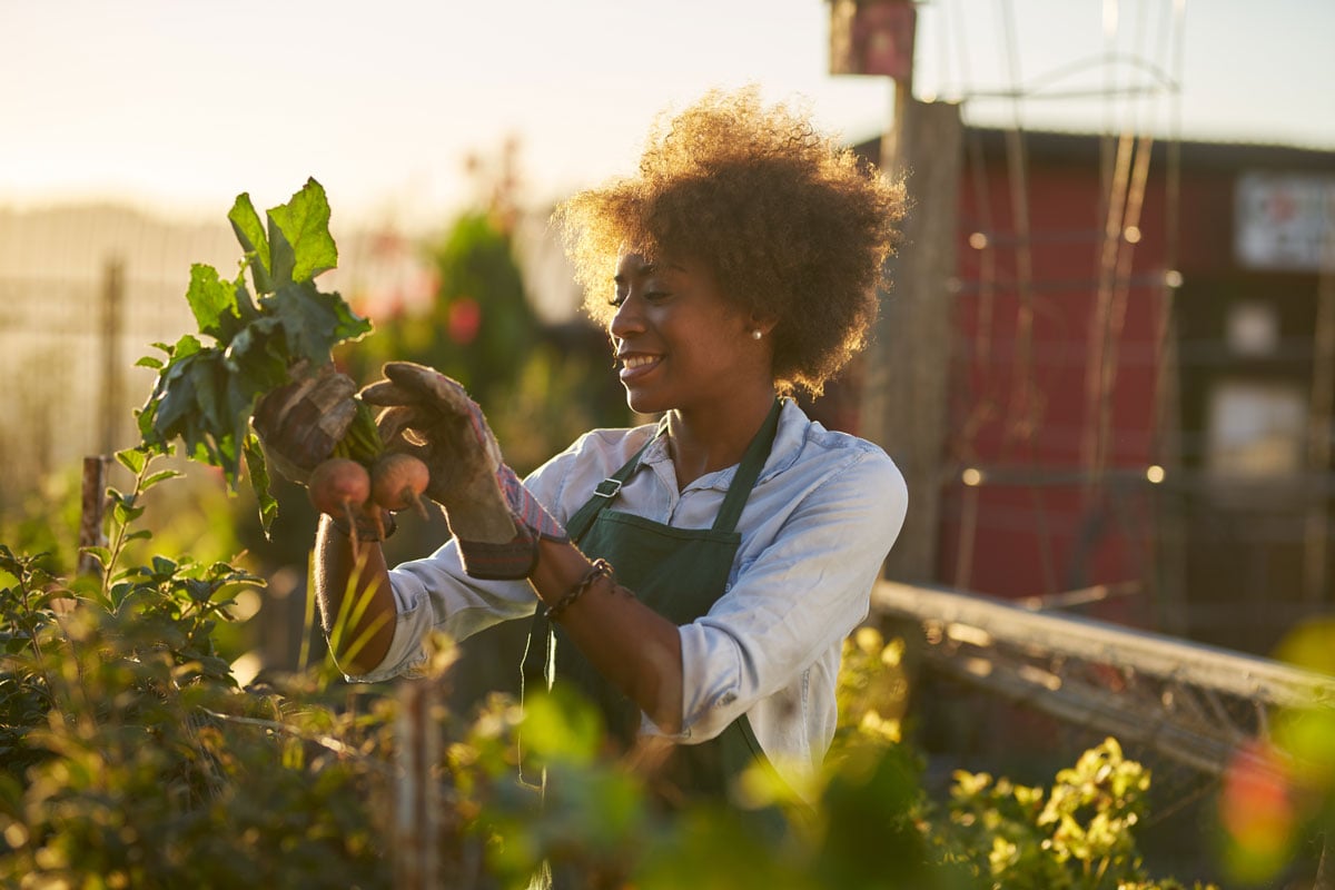 Woman gardening holding up vegetables